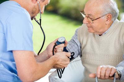 male nurse checking blood pressure of senior man