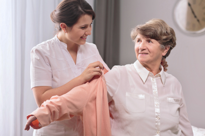 caregiver giving the sweater to older woman